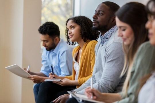 Group of people listening and taking notes.