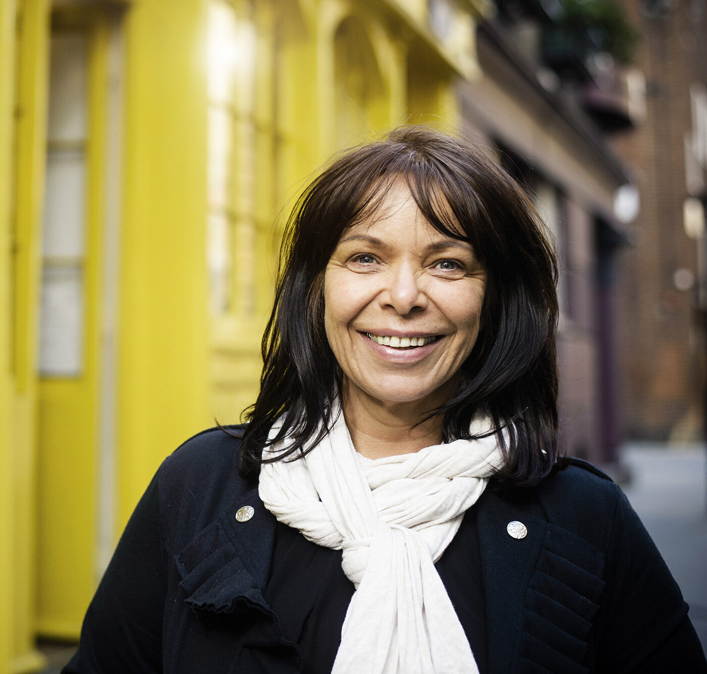 A woman wearing a white scarf smiles at the camera