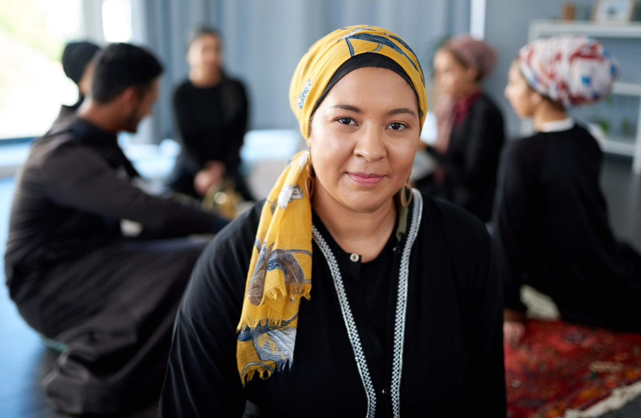 Portrait of a beautiful young muslim woman student at a gathering with friends indoors