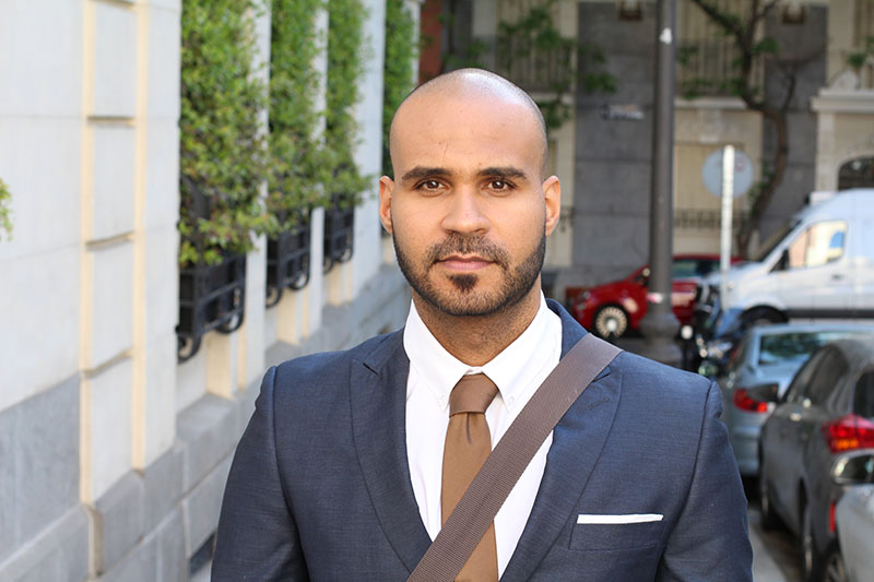A professional man wearing a suit walks on the street