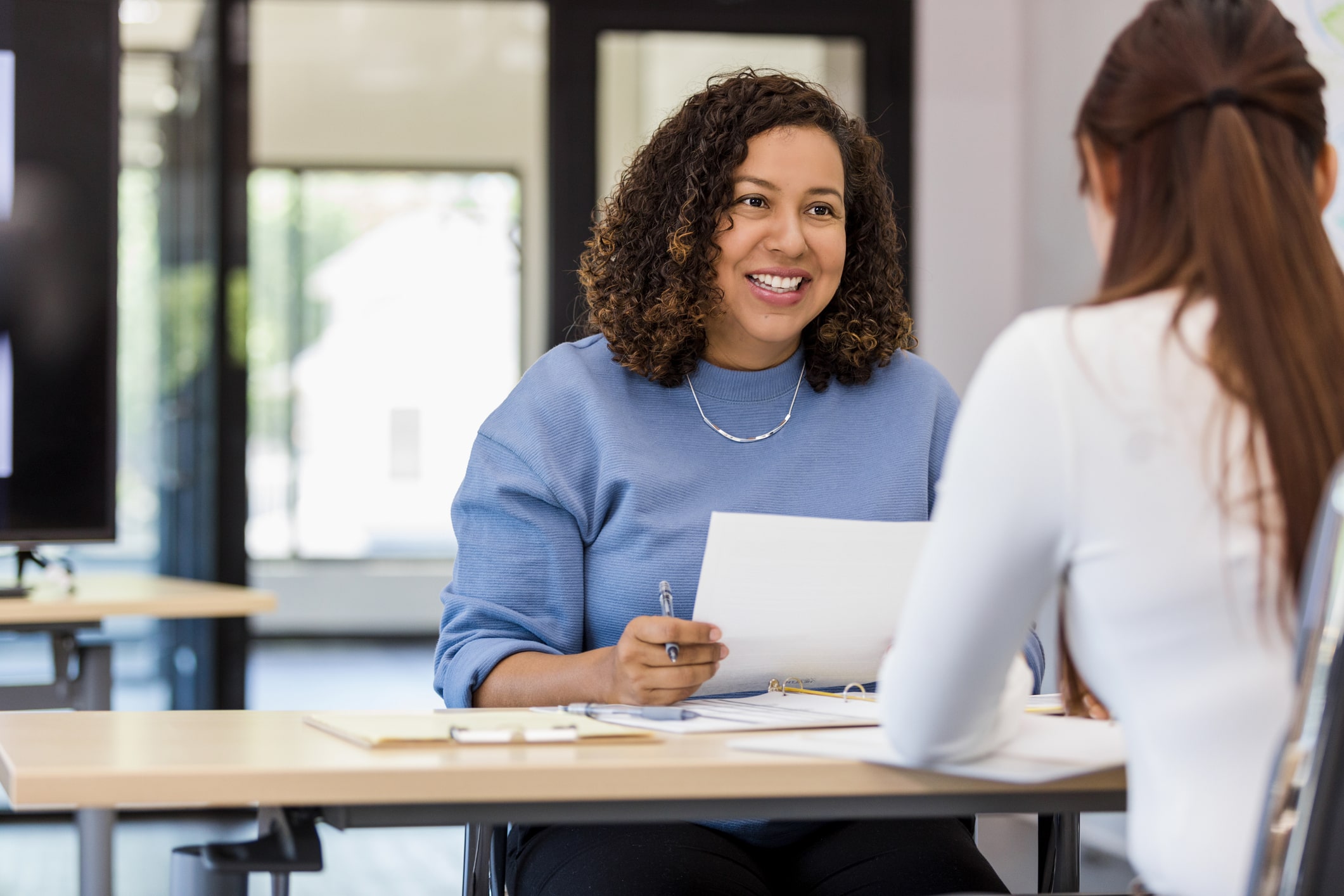 Two women having a discussion on the credential evaluation report while sitting at a desk