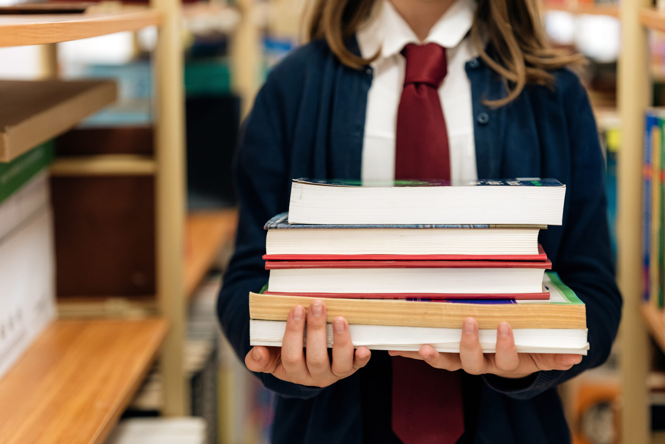 Close-up of female student holding a stack of books in the school library