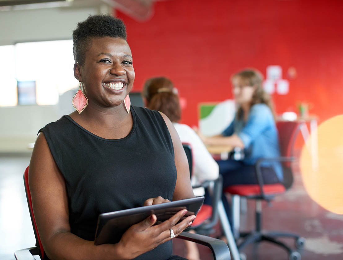 Woman smiling, holding tablet.