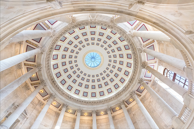 Looking up into the dome of a statehouse building with columns in a circle