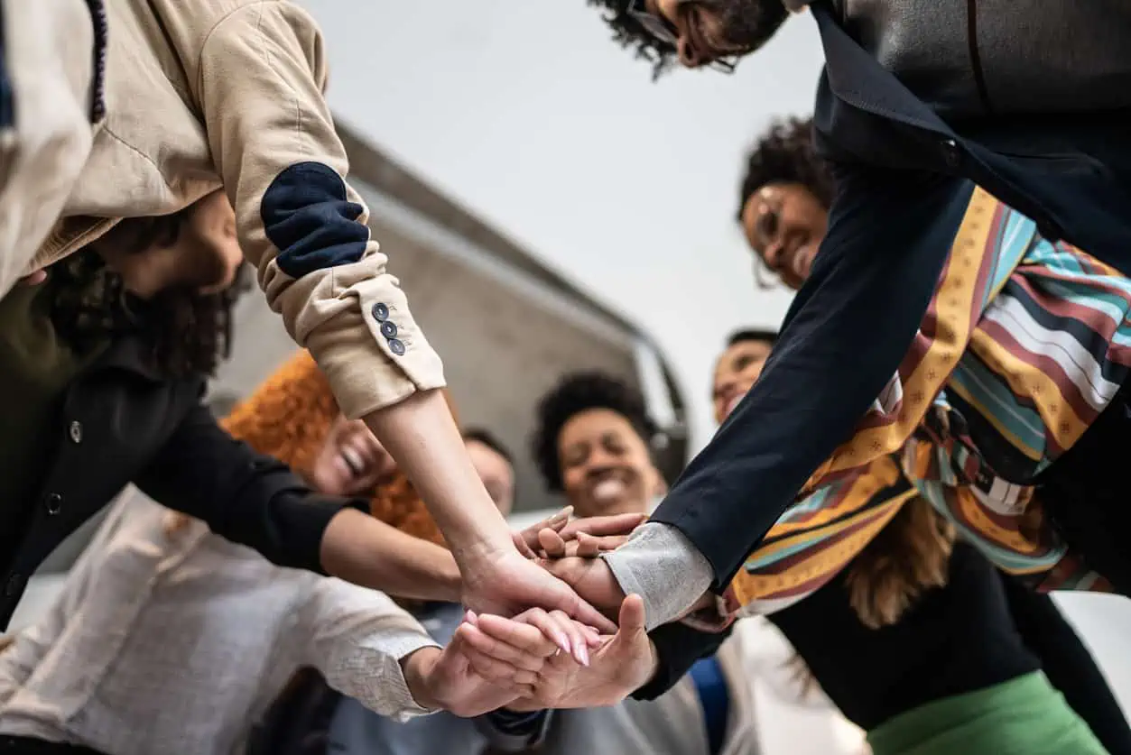 Group of students putting hands in the middle of a team huddle