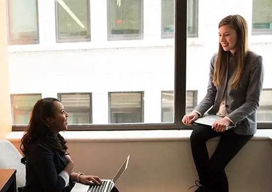 Professional women speaking to each other in window office